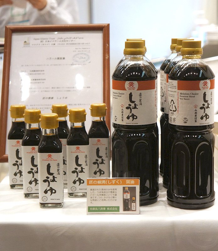 Botellas y botellines de salsa de soja halal junto con un certificado halal enmarcado.