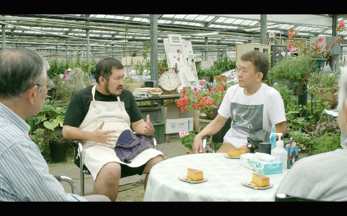 地元のラン園で東京国際映画祭の前プログラミング・ディレクター、矢田部吉彦さん（本人）を相手に熱弁をふるう渡辺。手前は実の両親　©cinemadrifters