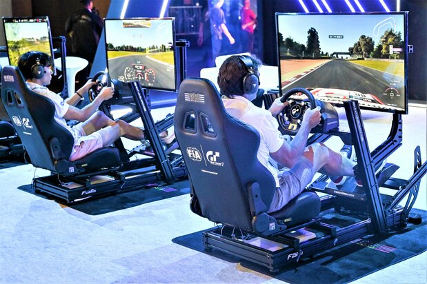 モータースポーツ競技の開始前、ソニー・インタラクティブエンタテインメント社の『グランツーリスモ7』でレース体験をする来場者たち。大会期間中は観客もさまざまなeスポーツを体感できた AFP=時事