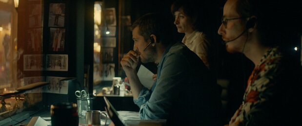 「時間旅行」を指揮するアントワーヌ(ギョーム・カネ)は、マジックミラーの背後に控え、イヤホンを仕込んだ役者にインカムで細かく指示を出す ©2019 - LES FILMS DU KIOSQUE - PATHÉ FILMS - ORANGE STUDIO - FRANCE 2 CINÉMA - HUGAR PROD – FILS – UMEDIA