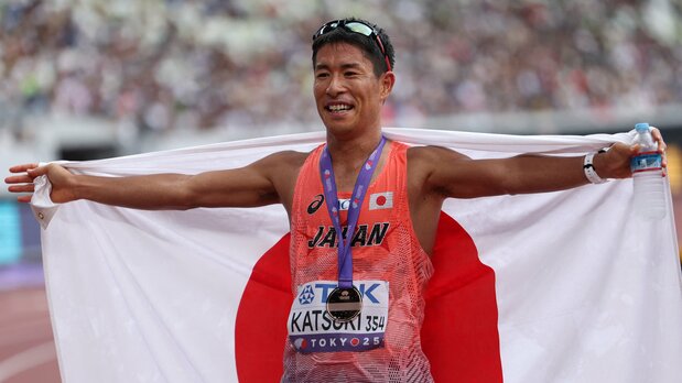 世界陸上男子35キロ競歩で、3位でゴールし日の丸を広げる勝木隼人=東京・国立競技場、2025年9月13日(ロイター)