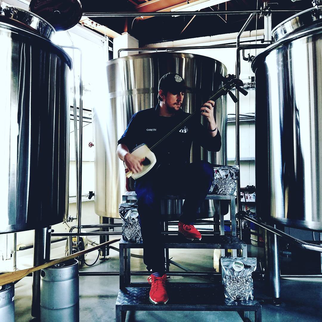 Gareth tocando un shamisen de Tsugaru rodeado de tanques de elaboración de cerveza. (Fotografía cortesía de Gareth Burns)