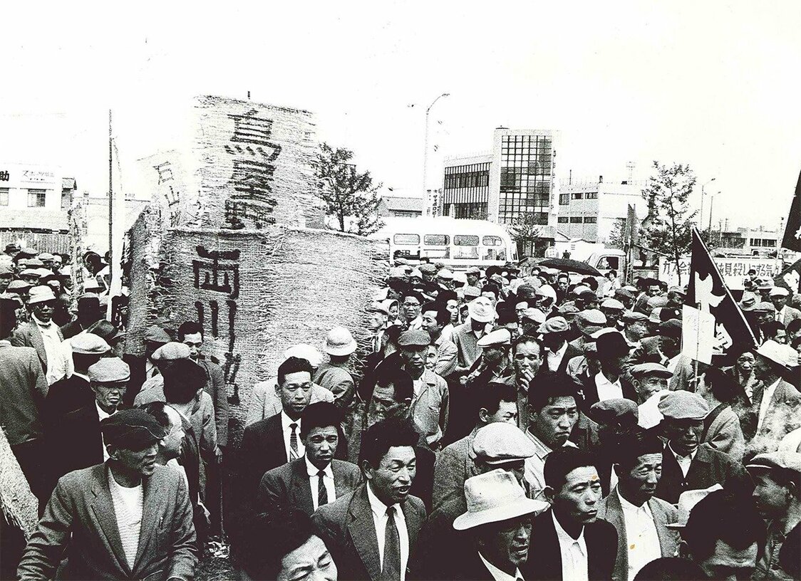 地盤沈下の被害を訴えて、亀田郷土地改良区の組合員は鳥屋野、両川、石山など地区ごとのむしろ旗を掲げ、新潟市内をデモ行進して県庁前広場に向かった。1959年11月19日 新潟市地盤沈下阻止市民大会　提供：亀田郷土地改良区