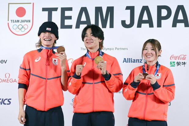 Snowboarding medalists smile during a February 15 press conference in Milan. From left, men’s snowboard halfpipe bronze medalist Yamada Ryūsei, gold medalist Totsuka Yūto, and women’s bronze medalist Ono Mitsuki. (© Jiji)