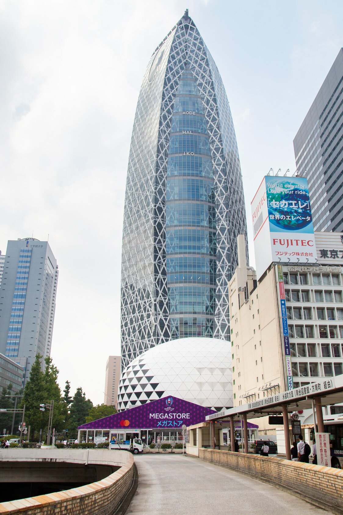 新宿西口を出ると、バスターミナルの向こうにメガストアが見える。西口のシンボル「コクーンタワー」が目印
