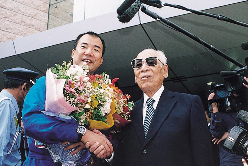 Andō shaking hands with astronaut Noguchi after his space mission.