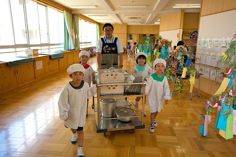 子どもたちと配膳用ワゴンを運ぶ担任の高木健示教諭。