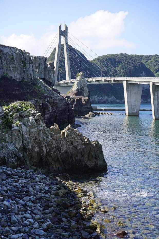 橋の袂(たもと)に連なる岩のひとつが甑(蒸し器)に見えることから「甑岩」と呼ばれ、島の名前の由来になった。この岩を島の人たちは大明神として崇める 写真:浮田泰幸
