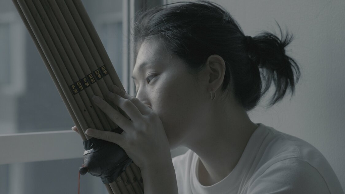 自宅でラオスの民族楽器ケーンを練習するコムアイ ©Toqué Studio LLC