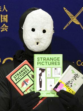 日本外国特派員協会(東京都千代田区)での会見で、『変な絵』の英語版を手にする雨穴氏(2025年1月 共同)