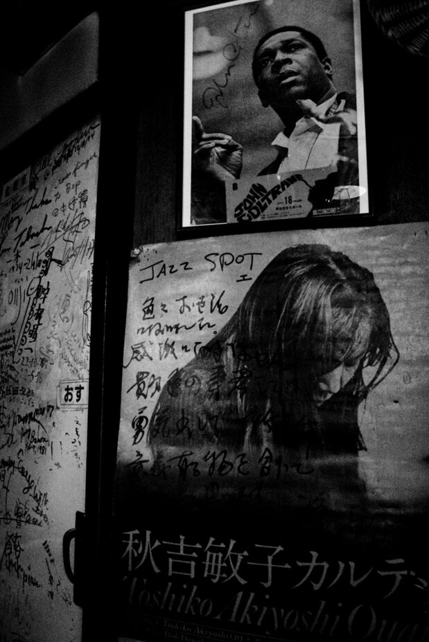Signed memorabilia from jazz greats covers the bathroom door. John Coltrane’s portrait above an Akiyoshi Toshiko poster.