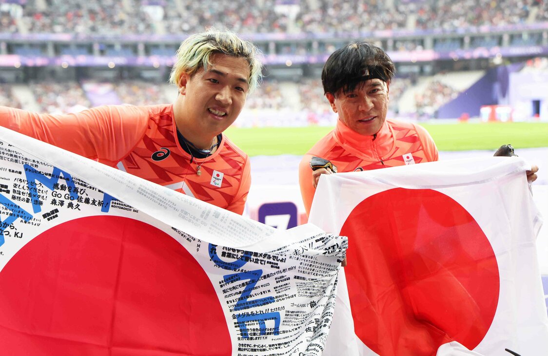 男子400メートル（車いすT52）決勝を終え、日の丸を掲げる銀メダルの佐藤友祈（左）と銅メダルの伊藤智也（時事）