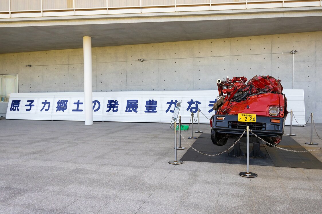 An outdoor exhibit of a fire truck crushed in the tsunami and a replica of a pro-nuclear-power slogan once displayed in the town.