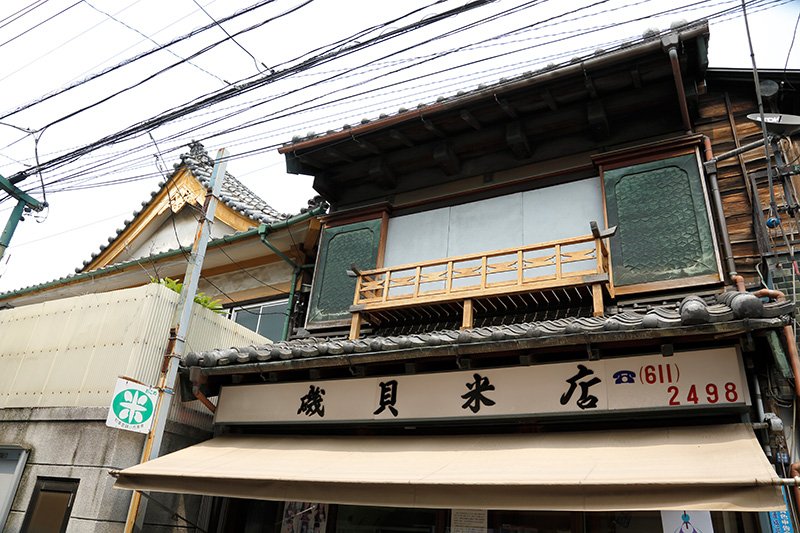 特徴的な戸袋、板壁、瓦の屋根の残る「磯貝米店」。