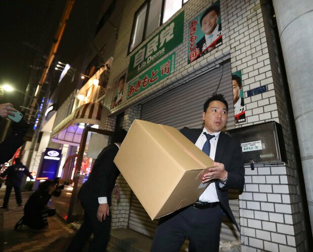 An official from the Tokyo District Public Prosecutors Office carries a box containing confiscated items from the office of House of Representatives member Akimoto Tsukasa in Kōtō ward, Tokyo, on December 19, 2019. (© Jiji)
