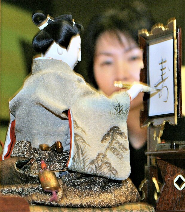 世界的にも珍しい、文字の書けるからくり人形。田中久重の江戸時代末期の作品で、ゼンマイ仕掛けで筆に墨をつけ、人間そっくりのしぐさで、和紙に「寿」「松」「竹」「梅」などの文字を書く 時事