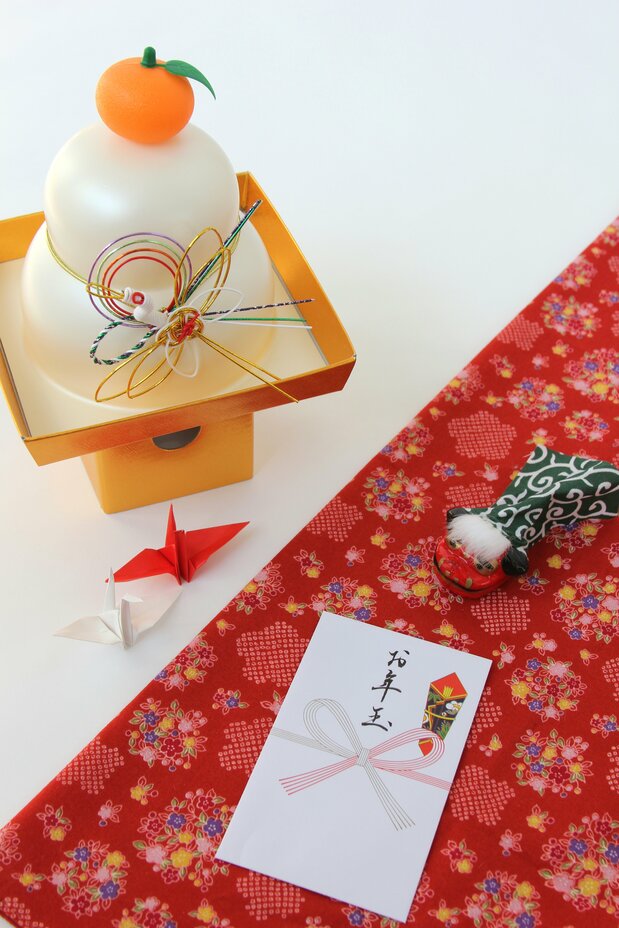Kagami mochi (à gauche) et pochi-bukuro (à droite). Cette enveloppe contient des étrennes (otoshi-dama). Pochi vient de « petit » et suggère qu’il s’agit d’une petite somme d’argent. (Pixta)
