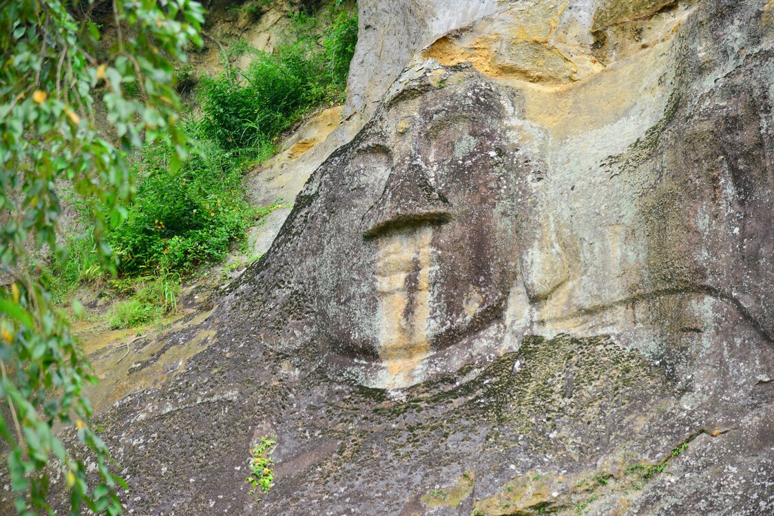 A large image of Buddha carved into the rock face.