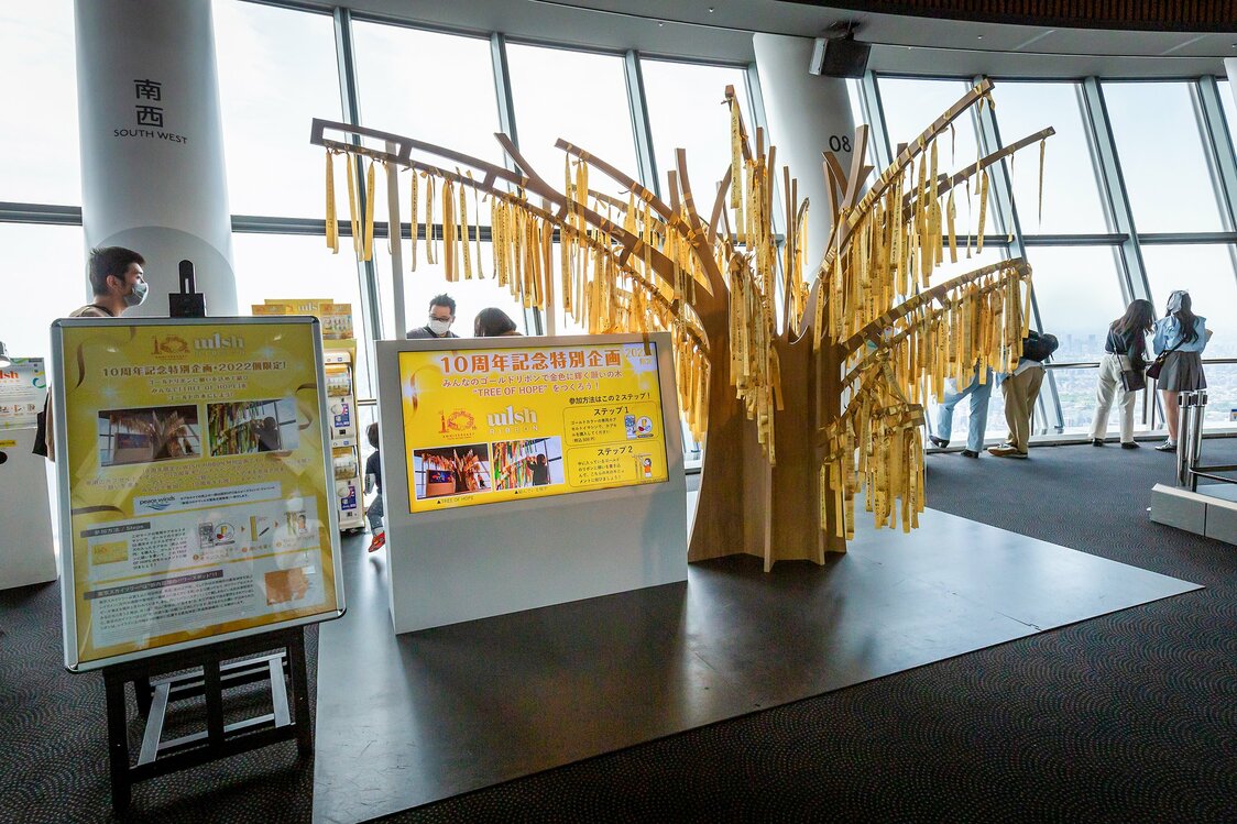 WISH RIBBON, proyecto conmemorativo del décimo aniversario, se encuentra en el mirador a 350 metros de altura. La torre Tokyo Skytree, el edificio más alto de Japón, es conocida como un lugar que concentra energía espiritual favorable.