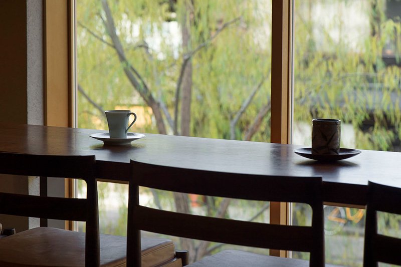 El café de después del desayuno se puede tomar en las mesas del primer piso (segundo en Japón) mientras se disfruta de la vista de los sauces a lo largo del río Shira,