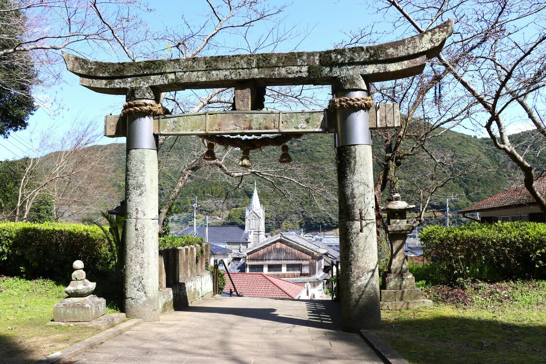 﨑津諏訪神社の鳥居内に納まる﨑津教会。異宗教共生を象徴する景観だ　写真＝天野久樹