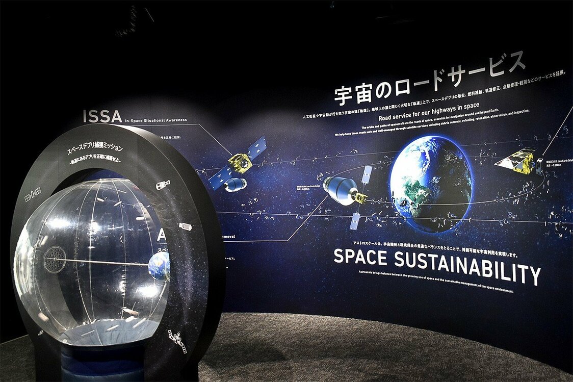 الزوار مدعوون لمحاولة التقاط الحطام الذي يلتف حول نموذج الأرض المضغوط بالهواء. (© Nippon.com)