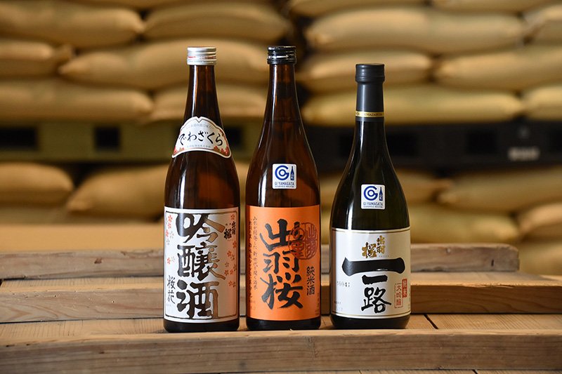 Productos bandera de Dewazakura Shuzō. De izquierda a derecha: Ōka Ginjōshu, que triunfó en 1980; Junmaishu Dewa no Sato, campeón de IWC en 2013; Junmai Daiginjō Ichiro, campeón de 2008.