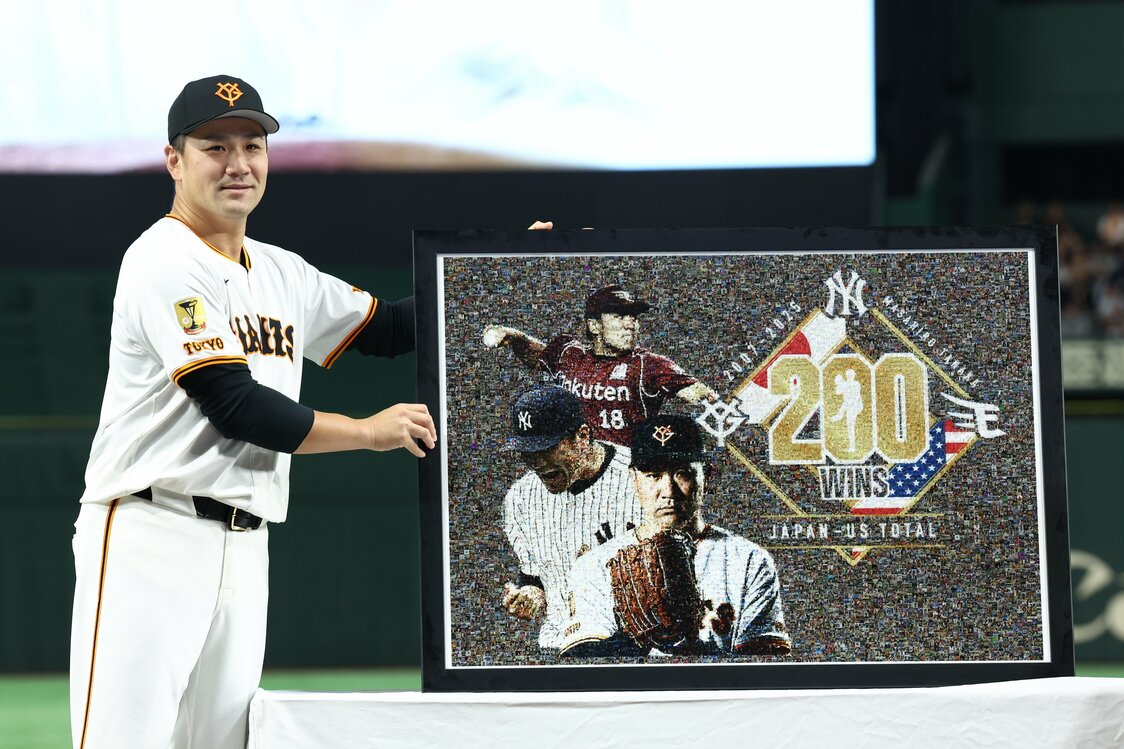 前日に日米通算200勝を達成し、セレモニーでモザイクアートを手に笑顔を見せる巨人の田中将大＝2025年10月1日、東京ドーム（時事）