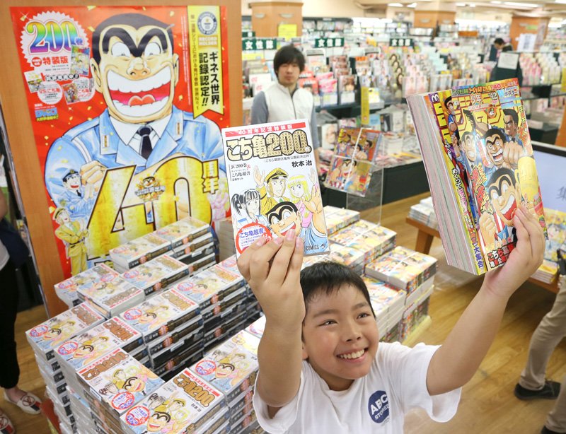 A boy holds the final volume of This is the Police Box in Front of Kameari Park, Katsushika and the edition of Weekly Shōnen Jump featuring its final appearance in the Kameari branch of Tsutaya in Katsushika, Tokyo, on September 17, 2016. (© Jiji)