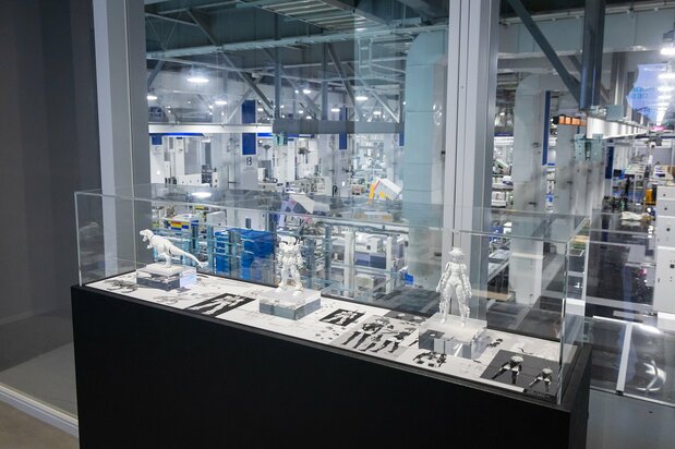 From the museum’s exhibition area, visitors can also view the factory floor. The showcase in front displays the three models available for the Plamo Designer Test: the Plannosaurus Tyrannosaurus (left), Gundam (center), and 30 Minutes Sisters’ Rishetta (right). (© Bandai Spirits, © Bandai Spirits 2021, © Sōtsū/Sunrise, © Nippon.com)