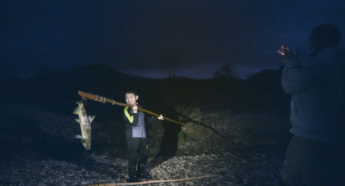 Motoki sostiene una presa con su marep. (© 2024 Takeshi Fukunaga/AINU PURI Production Committee)