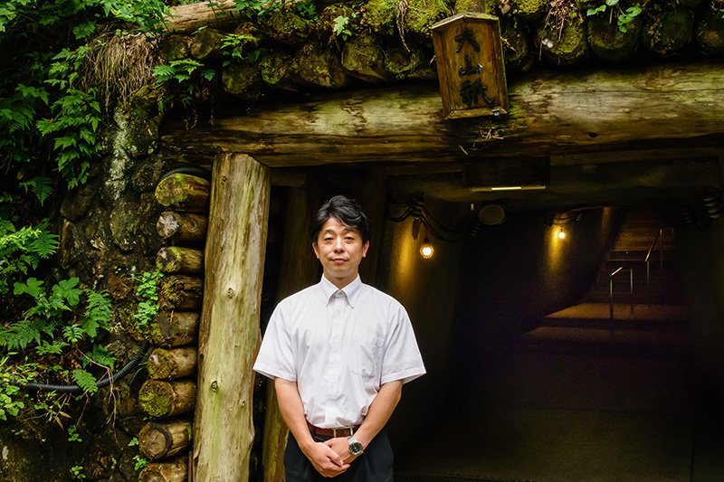Golden Sado employee Nabata Shō stands at the entrance of an old mining tunnel.