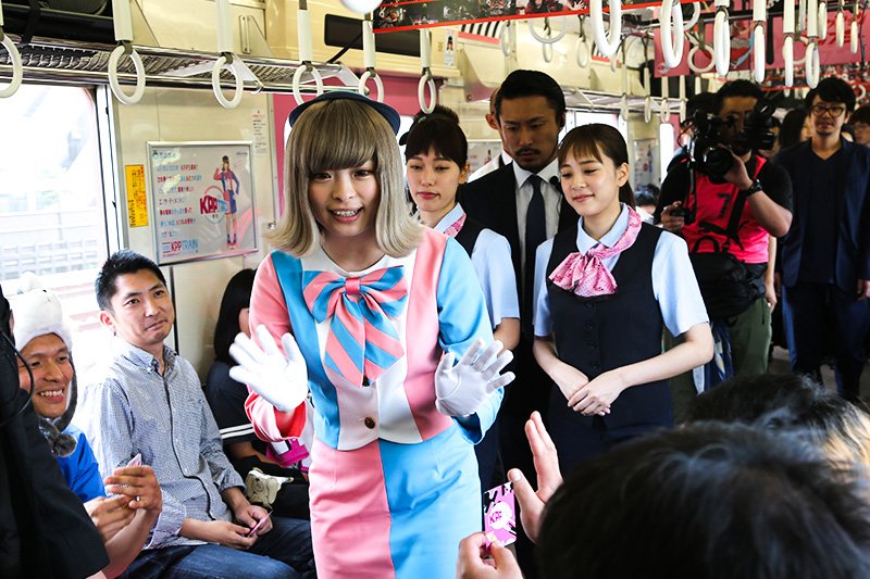 Kyari Pamyu Pamyu, ataviada de revisora, saluda a los aficionados que le muestran sus billetes.