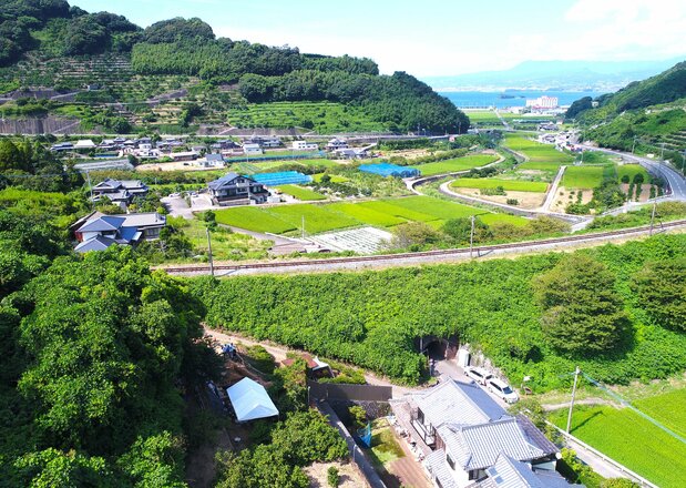 みかん畑に囲まれた高台の急斜面に立つ伊木力墓石(左下)。その前にはJRの線路が走り、遠くに大村湾が見える 写真提供=浅田昌彦