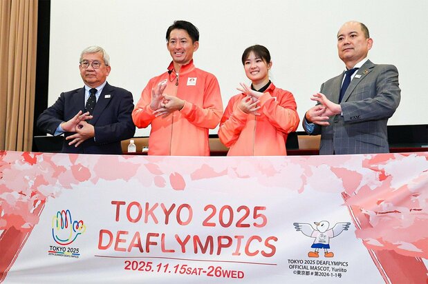 Posing with a gesture used in sign language at an October 2025 press conference for the Tokyo Deaflympics are, from left, Team Japan leader Ōta Yōsuke, men’s soccer team captain and flag bearer Matsumoto Takumi, women’s karate athlete Ogura Ryō, and Ishibashi Daigo, president of the Japanese Federation of the Deaf. (© Jiji)