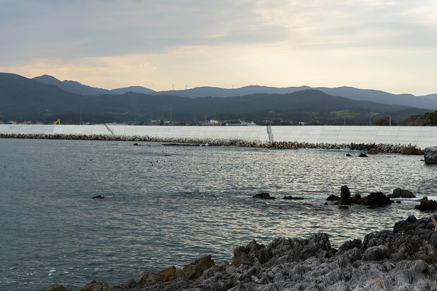 景勝地「岩井崎」から「気仙沼市 東日本大震災遺構・伝承館」(中央)を望む。海岸線には、高い防波堤が延々と築かれていた
