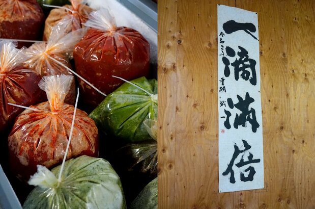 冷凍保存した状態の唐辛子各種(左)、平井さんの手による「一滴万倍」の書に思いがこもる(右)