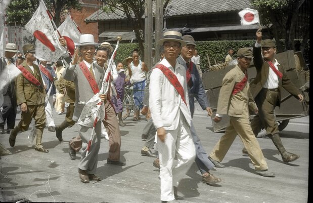 《武運昂然》1945年中壢的世家吳鴻麒、吳鴻煎兄弟的凱旋遊行。吳鴻麒在其兩年後於二二八事件中遭虐殺。（取自《彩繪鄧南光：還原時代瑰麗的色彩》）