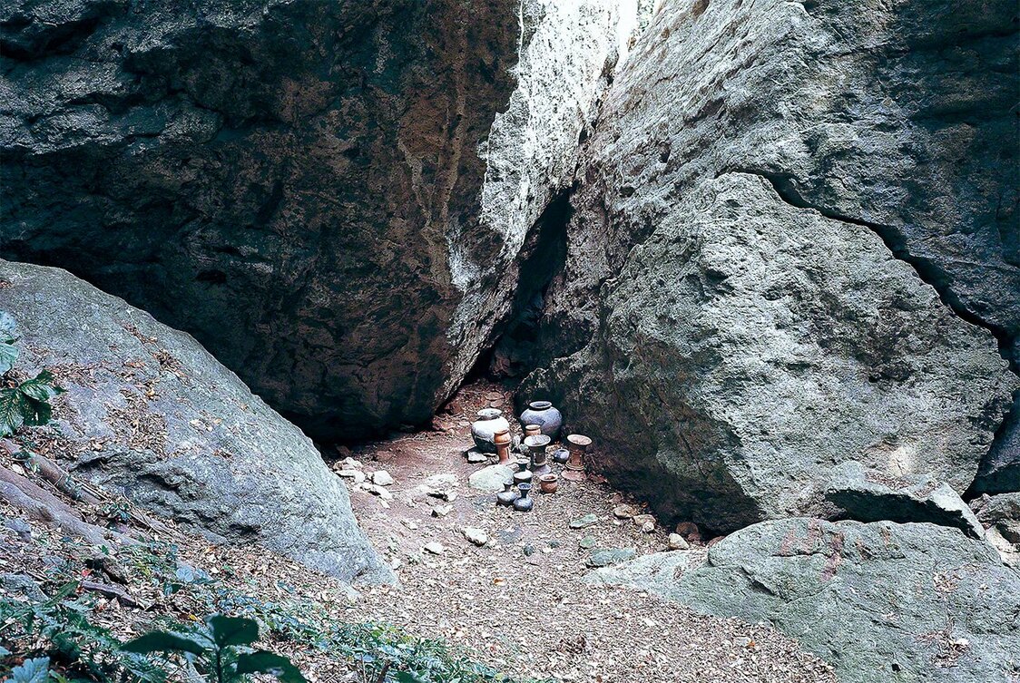 Excavation at Site 5. The crevice at the rear contained miniatures of a five-stringed harp, bobbins for spinning thread, and other objects. In the foreground are earthenware vessels used for offering rituals. (Courtesy of Munakata Taisha)