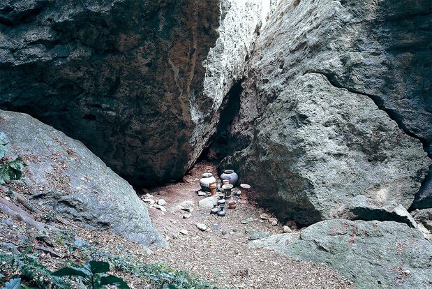 Excavation at Site 5. The crevice at the rear contained miniatures of a five-stringed harp, bobbins for spinning thread, and other objects. In the foreground are earthenware vessels used for offering rituals. (Courtesy of Munakata Taisha)