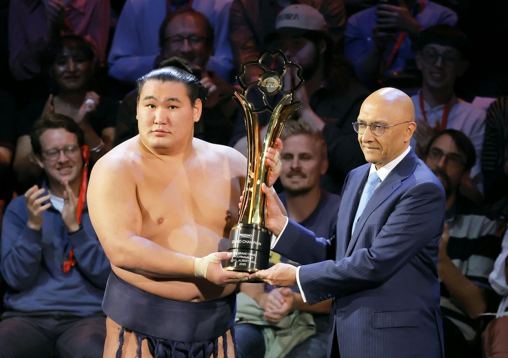 Hōshōryū, left, hoists the trophy after defeating Ōnosato to win the tournament on October 19 at London’s Royal Albert Hall. (© Kyōdō)