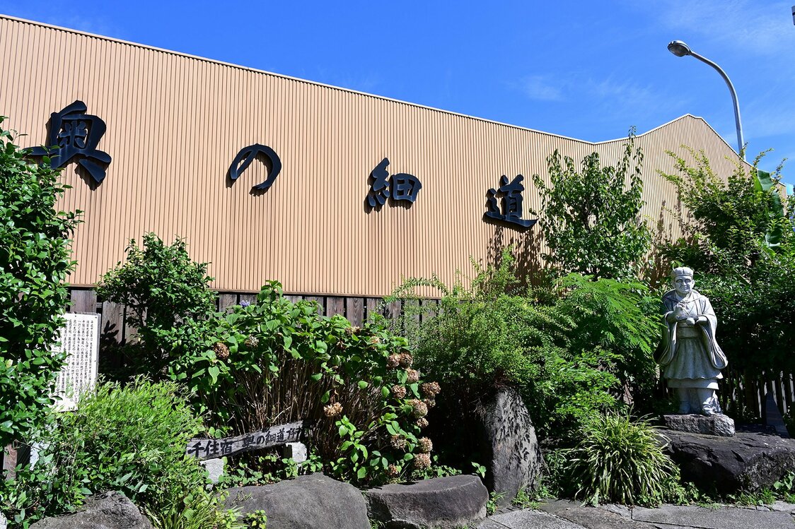 芭蕉の石像が置かれる、足立区側の旧街道入り口にある「千住宿 奥の細道プチテラス」