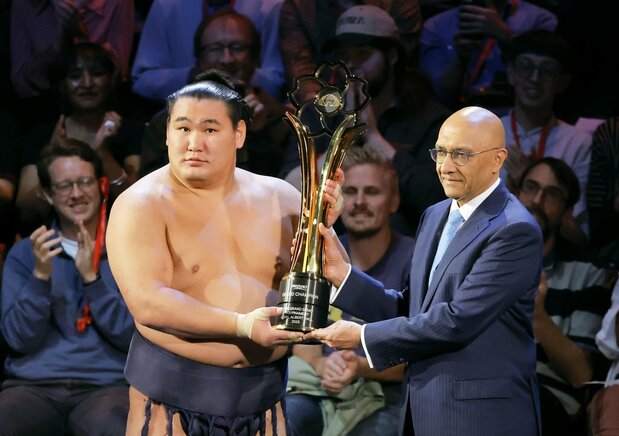 Hōshōryū, left, hoists the trophy after defeating Ōnosato to win the tournament on October 19 at London’s Royal Albert Hall. (© Kyōdō)