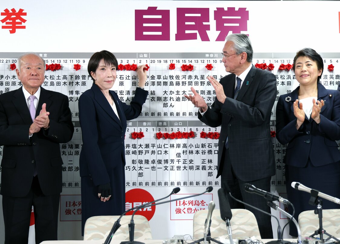 開票センターで当選確実となった候補者の名前に花を付ける高市早苗首相（中央左）（時事）