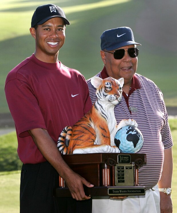2004年12月の大会で優勝したタイガー・ウッズ選手と共に記念撮影に応じるアール・ウッズ氏(右) ロイター=共同