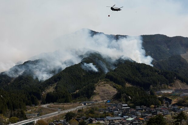 A helicopter releases water to tackle the blaze in Ōtsuchi on April 26. (© Reuters)