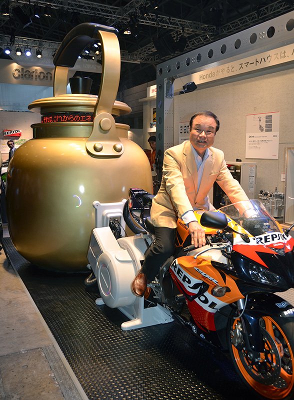 巨大なやかんにつながったバイクにまたがるホンダの伊東孝紳社長