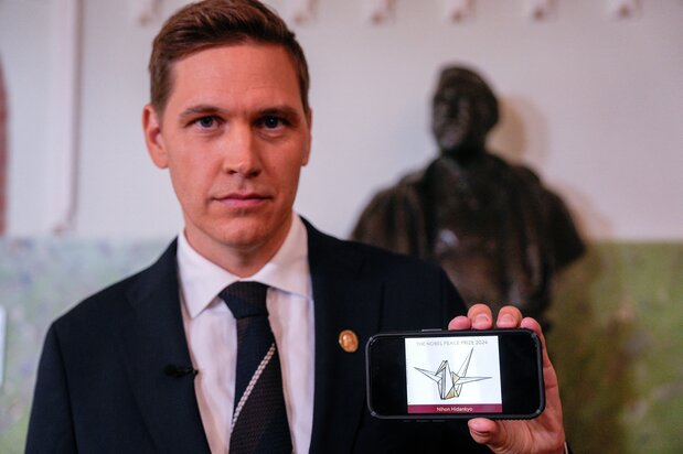 Joergen Frydnes, Nobel Peace Prize committee chair, shows the Nihon Hidankyō logo at the press conference announcing the winner of the prize. (© Reuters)