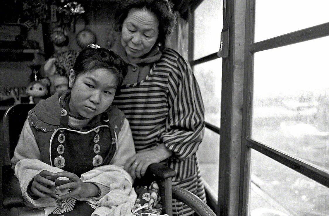 Tanaka Jitsuko à l’âge de 18 ans, en compagnie de sa mère. Elle est en train de regarder la mer à travers les fenêtres de la maison familiale. (Photo prise en 1971)