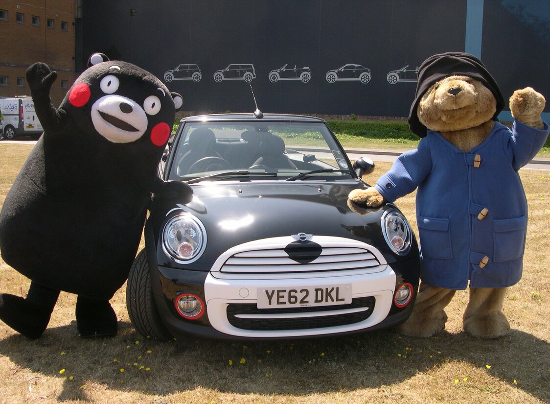 パディントンベア（右）と一緒に、BMWの特別仕様車「くまモンMINI」を披露するくまモン＝2013年7月11日、英国オックスフォード（時事）